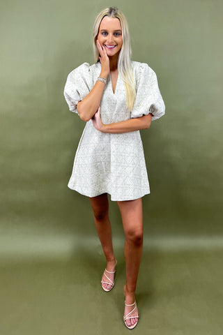 Woman wearing a white dress against a green background