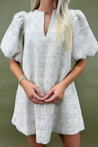 Woman wearing a white patterned dress against a green background