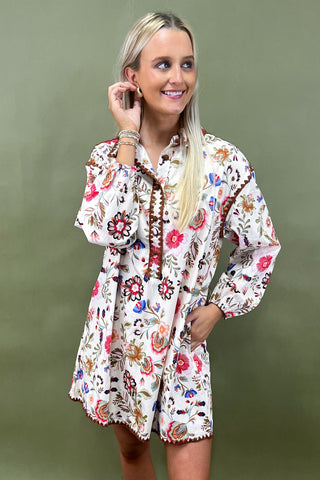 Woman wearing a floral embroidered dress against a green background