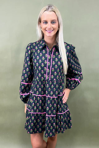 Woman wearing a floral dress with pink accents against a green background