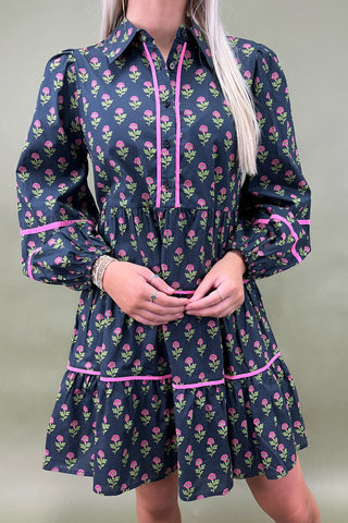 Person wearing a floral dress with pink accents on a plain background