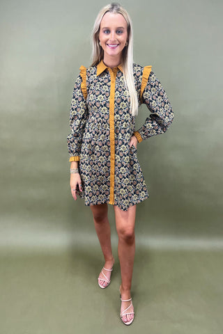 Woman wearing a floral dress with yellow accents against a green background