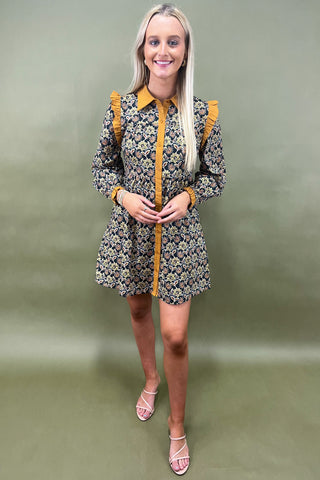 Woman wearing a floral dress with yellow accents against a plain background