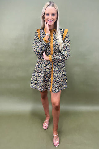 Woman wearing a floral dress with yellow accents against a green background