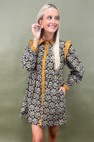 Woman wearing a floral dress with mustard yellow accents against a green background