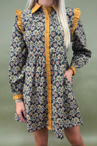 Floral dress with yellow accents worn by a person on a green background