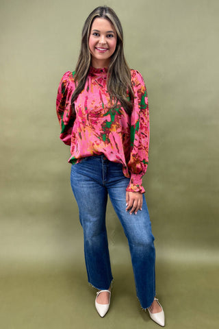 Woman wearing a pink floral blouse and blue jeans on a green background
