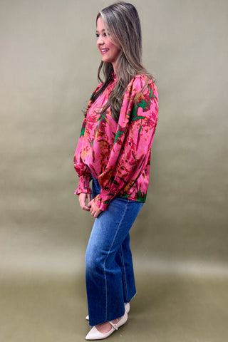 Woman wearing a pink floral blouse and blue jeans against a beige background