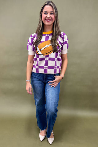 Woman wearing a checkered shirt with a football design and blue jeans on a beige background