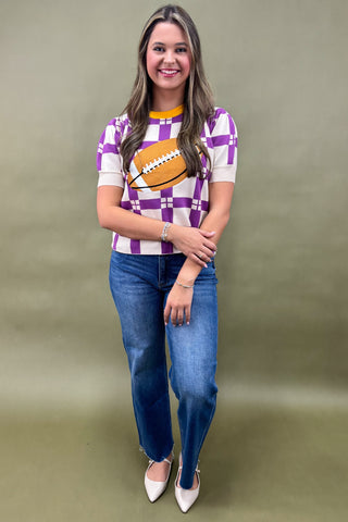 Woman wearing a checkered shirt with a football design and blue jeans on a beige background