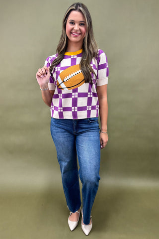 Woman wearing a checkered shirt with a football design and blue jeans on a green background