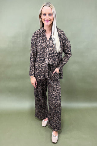 Woman wearing a leopard print outfit against a plain background