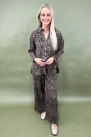 Woman wearing a leopard print outfit against a plain background