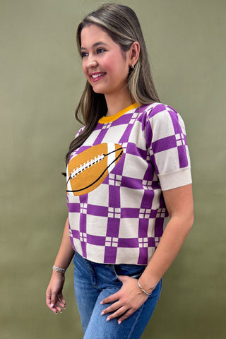 Woman wearing a purple and white checkered shirt with a football graphic on a green background