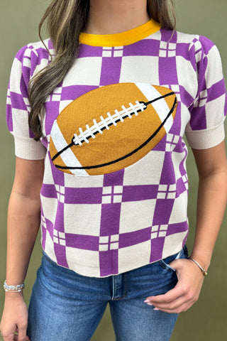 Person wearing a purple and white checkered shirt with a football graphic on a green background