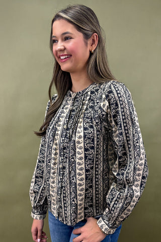 Woman wearing a patterned blouse against a plain background