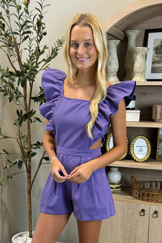 Woman in a purple outfit standing in a room with decorative elements.