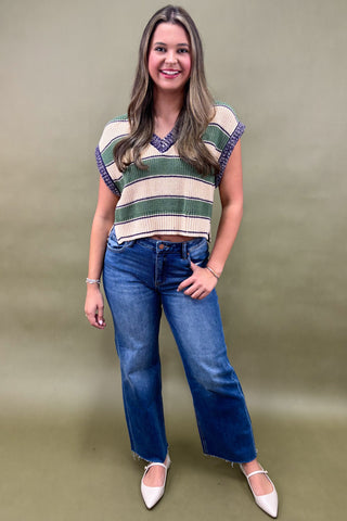 Woman wearing a striped sweater and blue jeans against a plain background