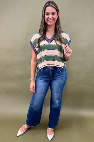 Woman wearing a striped shirt and blue jeans against a plain background