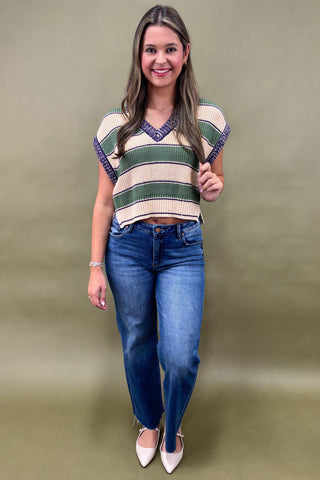 Woman wearing a colorful striped shirt and blue jeans against a plain background
