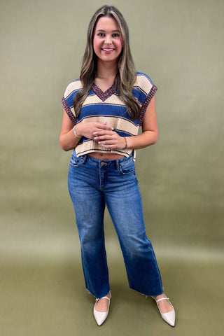 Woman wearing a striped sweater and blue jeans against a green background