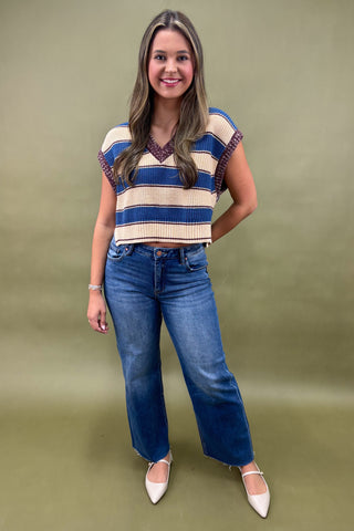 Woman wearing a striped top and blue jeans against a green background