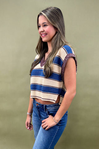 Woman wearing a striped crop top and jeans against a green background