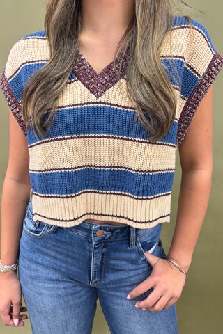 Person wearing a striped sweater and jeans against a plain background