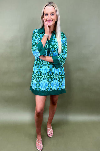 Woman wearing a green patterned dress against a plain background