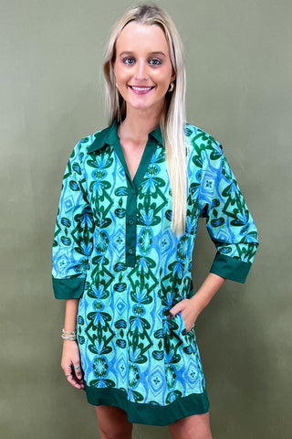 Woman wearing a green and blue patterned dress against a plain background