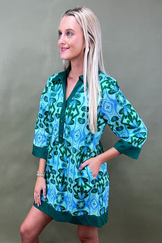 Woman wearing a green and blue patterned dress against a gray background