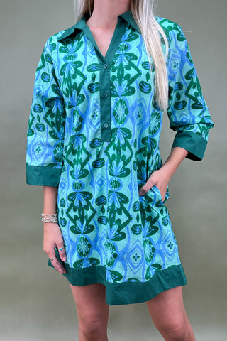 Woman wearing a green and blue patterned dress against a neutral background
