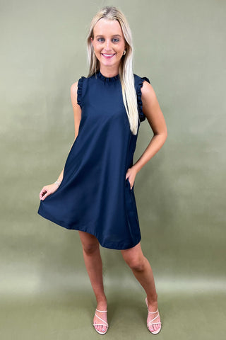 Woman wearing a navy blue dress against a green background
