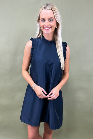 Woman wearing a navy dress against a plain background