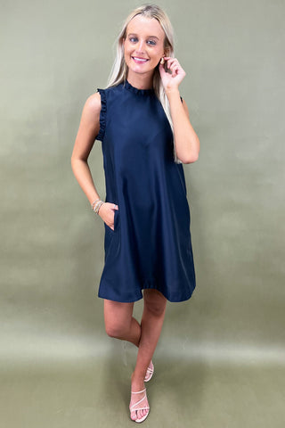 Woman wearing a navy blue dress against a green background