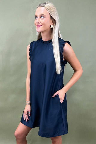 Woman wearing a navy blue dress against a green background