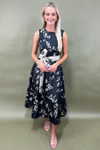 Woman wearing a black floral dress against a plain background