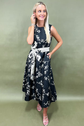 Woman wearing a black floral dress against a green background