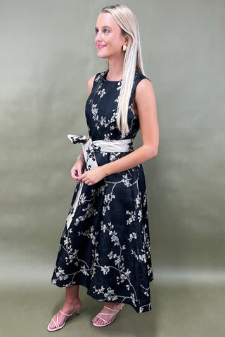 Woman wearing a black floral dress against a plain background