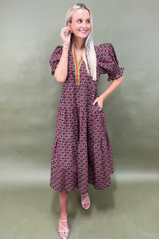 Woman wearing a patterned dress against a plain background