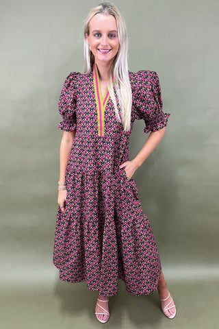 Woman wearing a patterned dress against a plain background