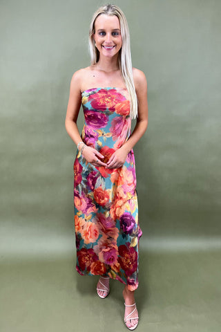 Woman wearing a strapless floral dress against a plain background