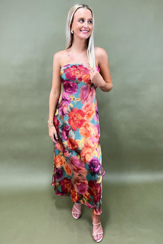 Woman wearing a colorful floral dress against a plain background