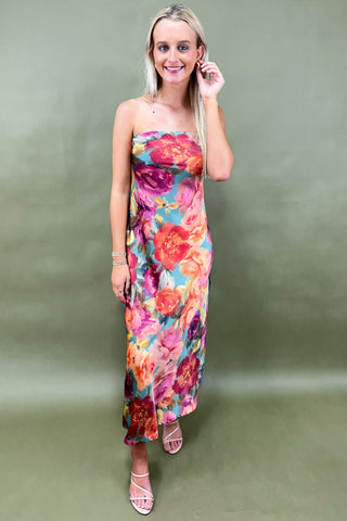 Woman wearing a colorful floral dress against a plain background
