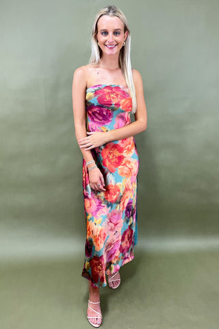 Woman wearing a colorful floral dress against a plain background