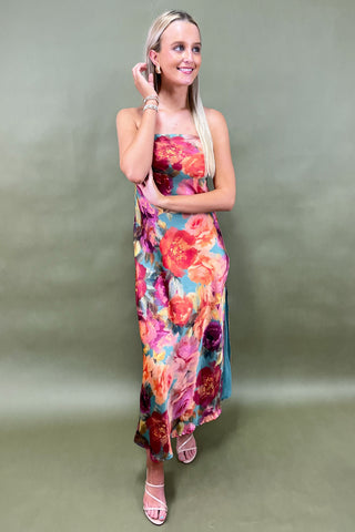 Woman wearing a colorful floral dress against a plain background