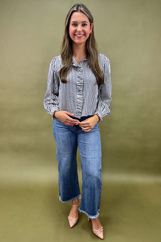 Woman wearing a striped shirt and jeans against a green background