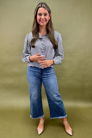 Woman wearing a striped shirt and blue jeans against a green background