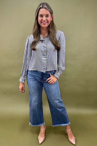 Woman wearing a striped shirt and blue jeans against a green background