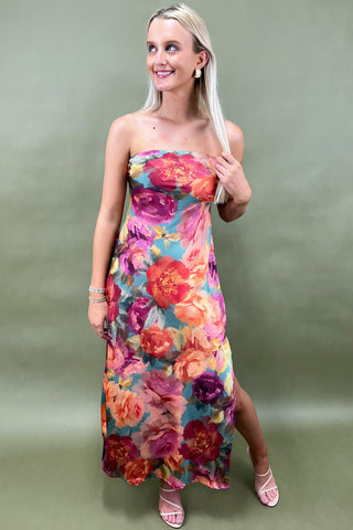 Woman wearing a strapless floral dress against a plain background